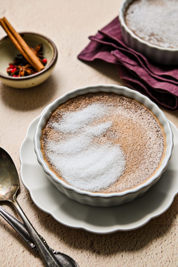 Baked mulled wine creme brulee in a ramekin with sugar placed on top.