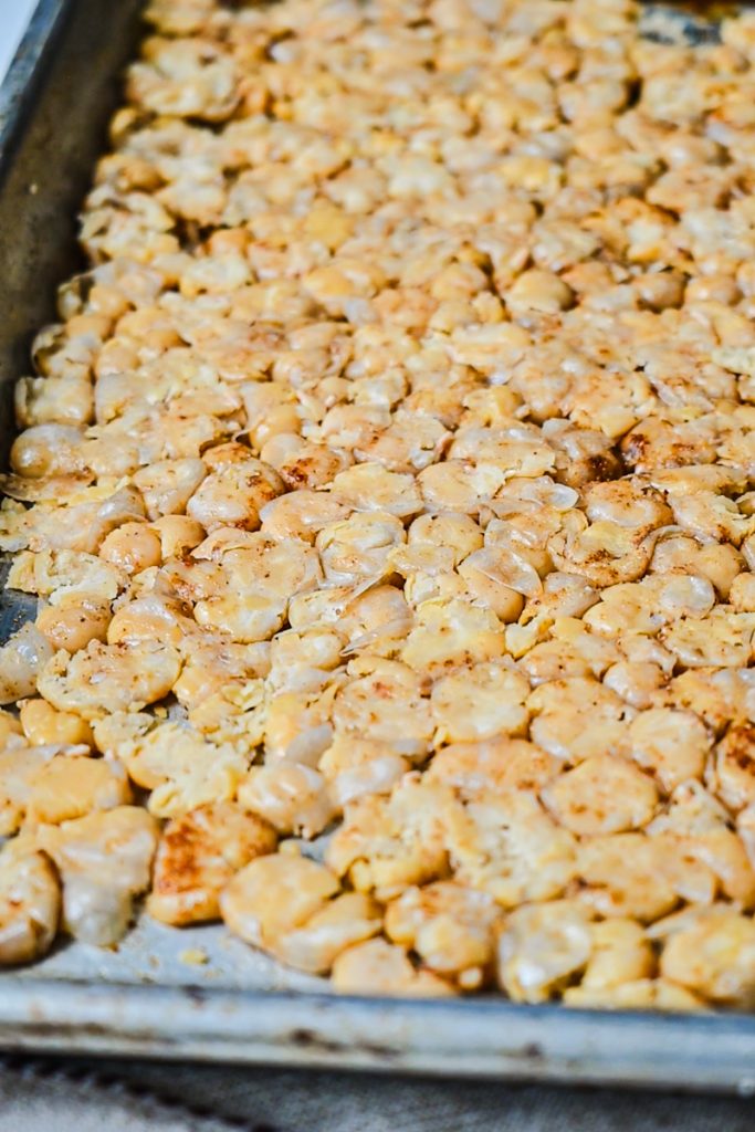 Smashed chickpeas on a sheet pan before baking.