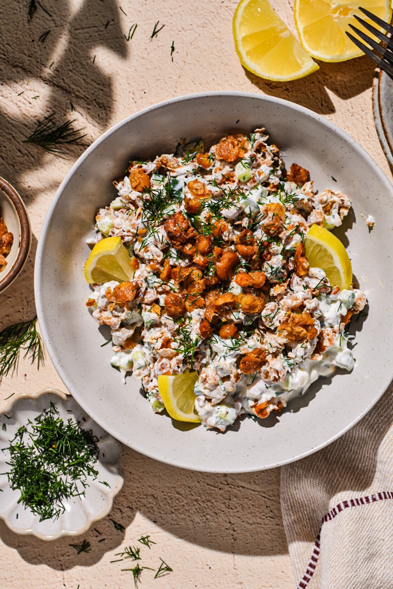 Crispy smashed chickpea salad in a bowl garnished with dill and lemon slices.
