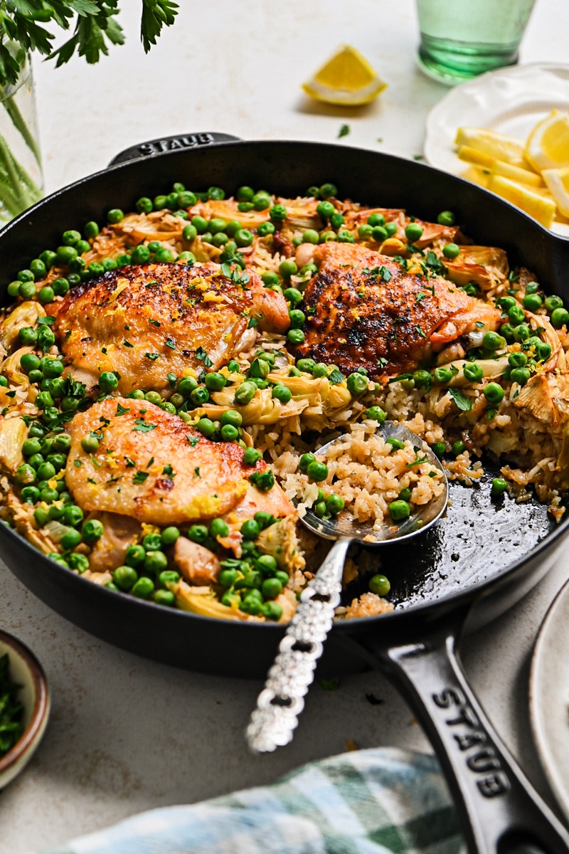 Side view of one pan lemon chicken and rice in a skillet with a serving spoon.