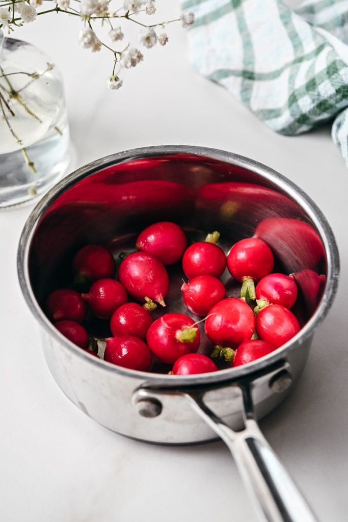 Fresh whole radishes in a sauce pan.