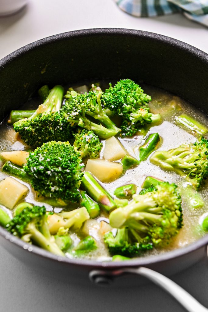 Broccoli and asparagus added to the skillet with some broth.