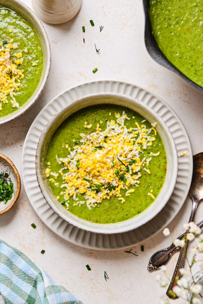 Green garden soup served in a bowl topped with grated boiled eggs.