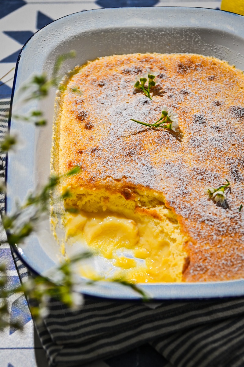Side view of lemon pudding cake in a baking dish with a portion missing.