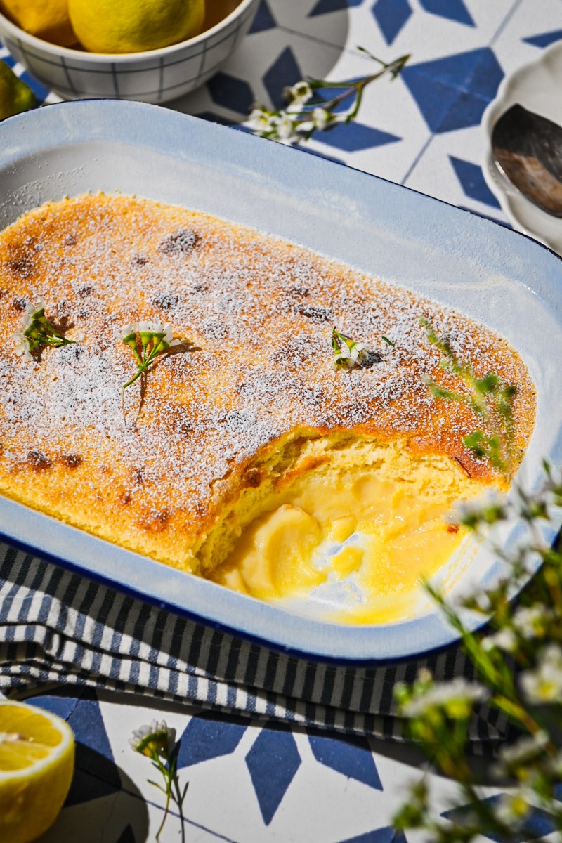 Baked lemon pudding cake in a baking dish with a portion missing.