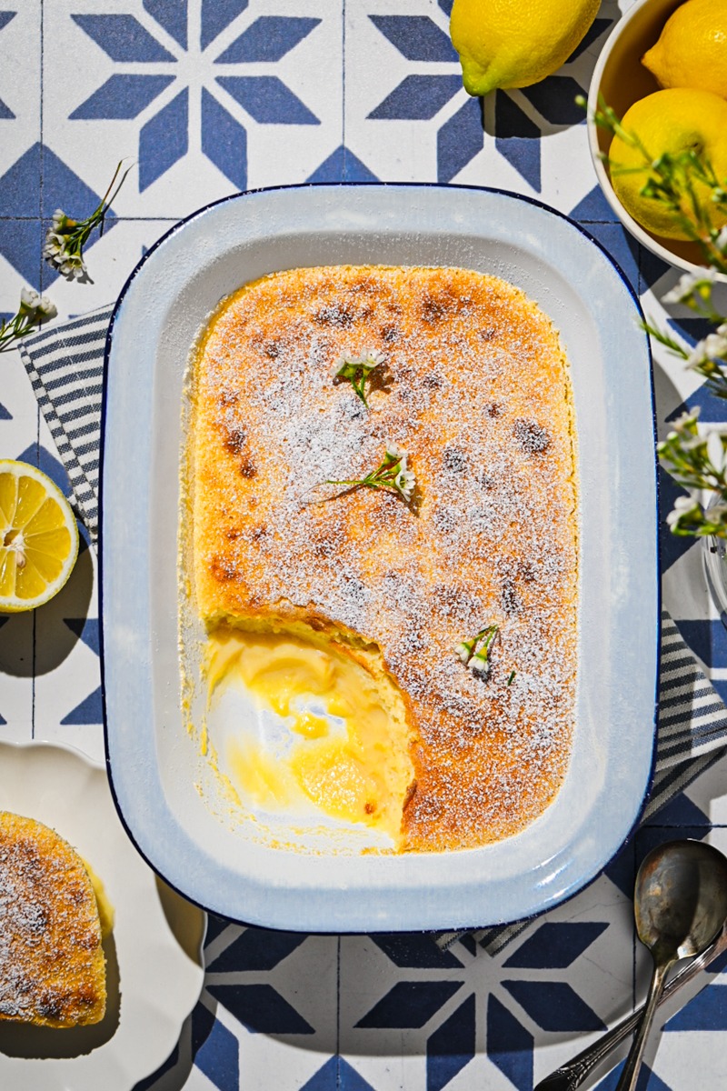 Overhead shot of lemon pudding cake in a baking dish with a portion missing.