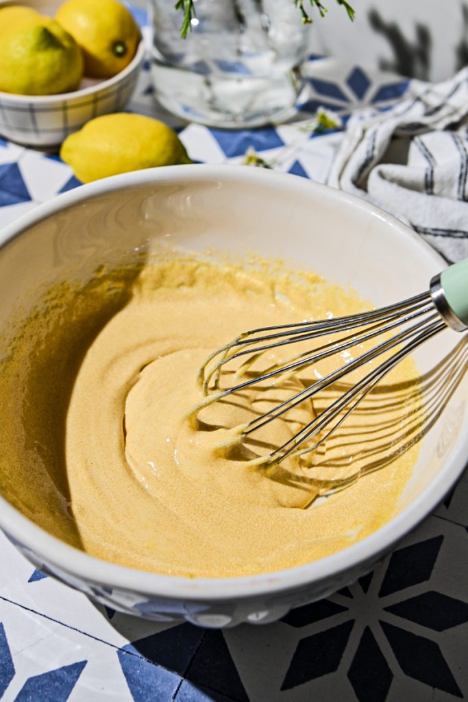 Mixing egg yolks and sugar in a mixing bowl with a whisk.