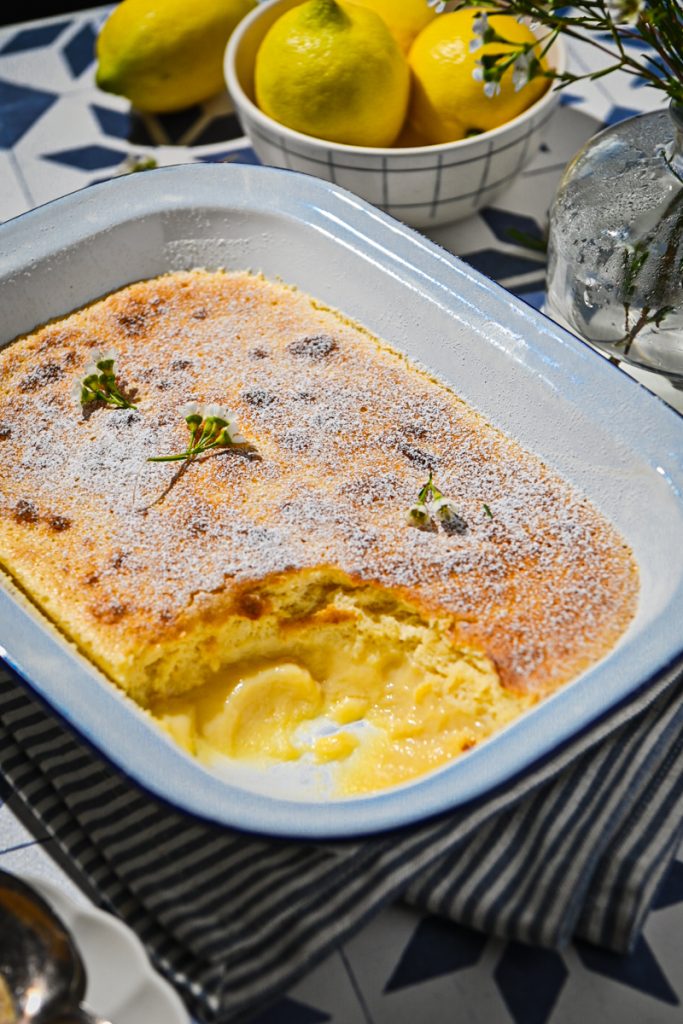 Side view of lemon pudding baked in a baking dish with a portion missing from the corner.