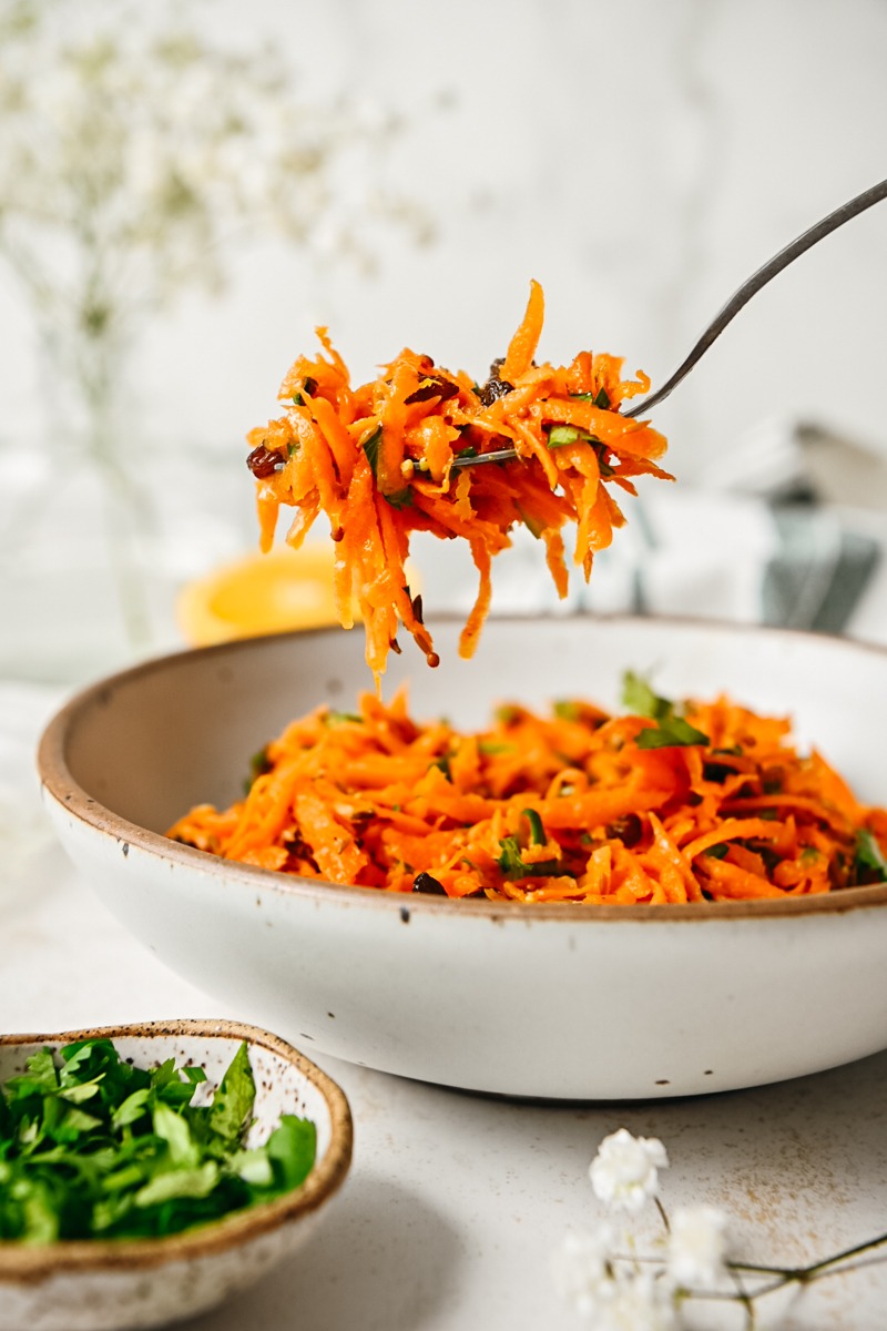 Fork with Moroccan carrot salad scooping some up from a bowl.