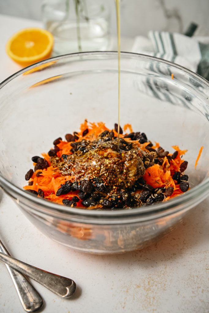 Honey drizzled into the carrot salad in a bowl.