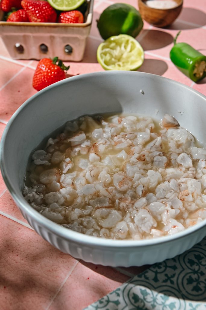 Shrimp in a bowl cooking with lime juice.