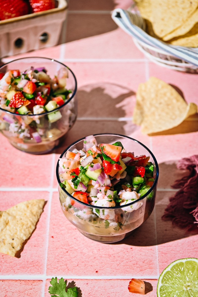 Two glasses of strawberry shrimp ceviche with tortilla chips around.