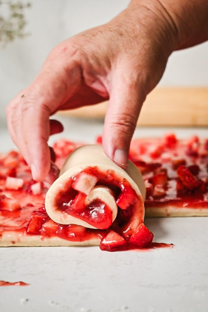 Hand rolling up the strawberry filled dough.