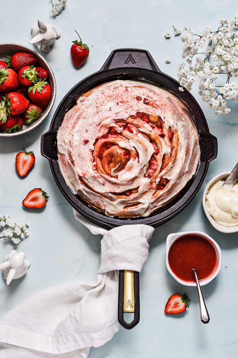 Overhead shot of giant strawberry roll cake with a cream cheese glaze on top.