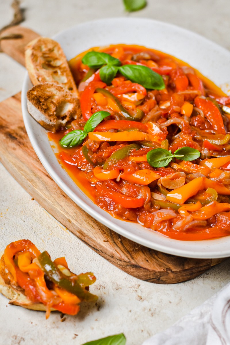 Pepperonata served on a serving platter next to crusty bread.