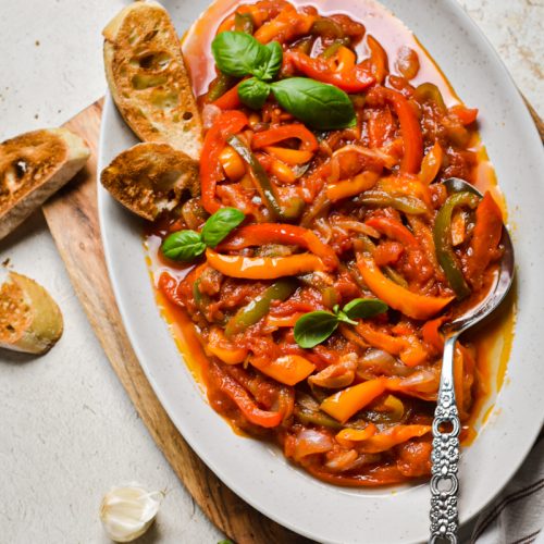 Overhead shot of peperonata served in a serving dish with a silver spoon.