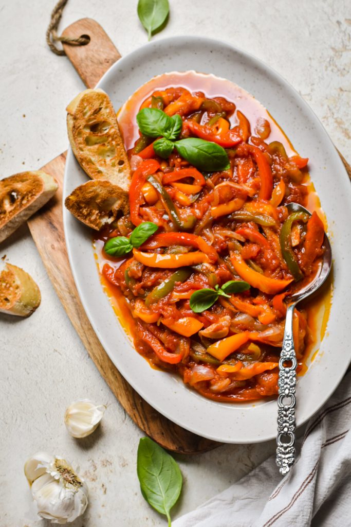 Overhead shot of peperonata served in a serving dish with a silver spoon.