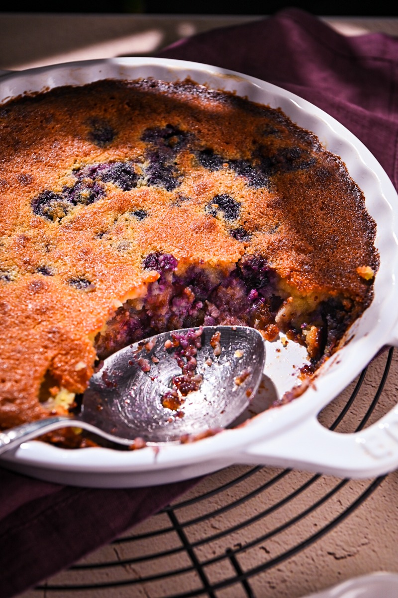 Side view of baked blueberry rhubarb gratin with a piece missing.