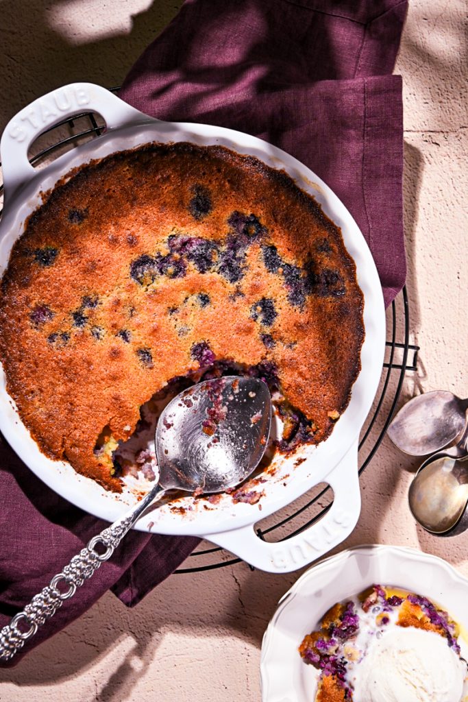 Overhead shot of blueberry rhubarb gratin in a white baking dish with a serving spoon.