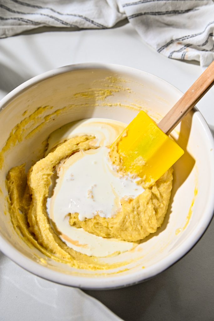 Heavy cream added to the batter in a mixing bowl.