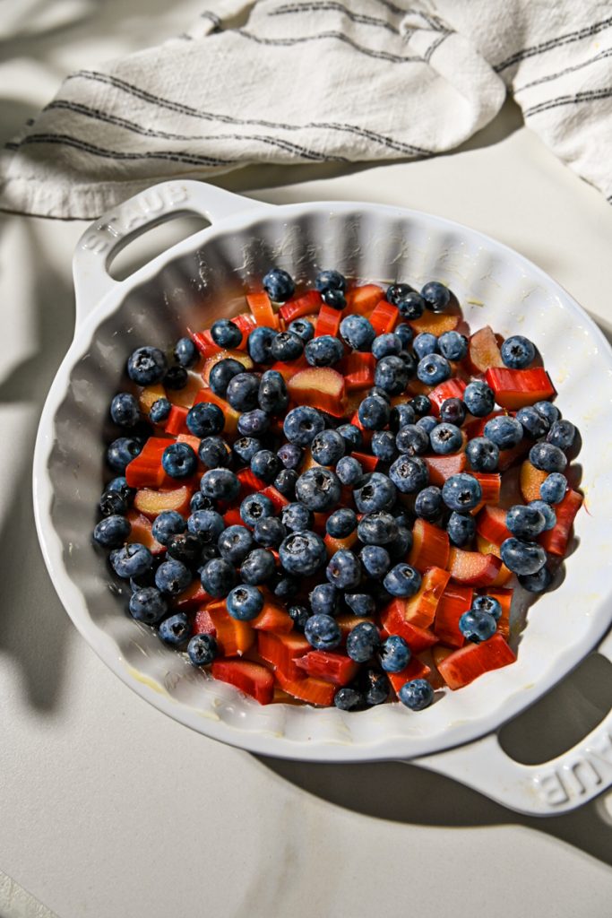 Diced rhubarb and fresh blueberries in the bottom of a pie dish.
