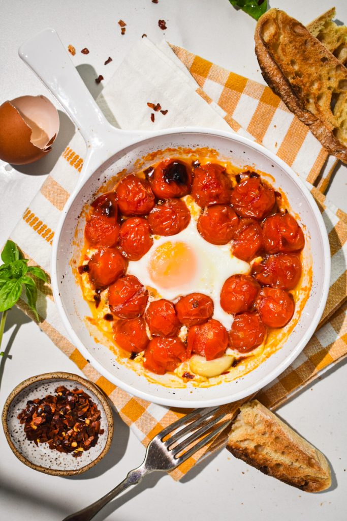 Overhead shot of eggs in purgatory with fresh tomatoes in a small baking dish.