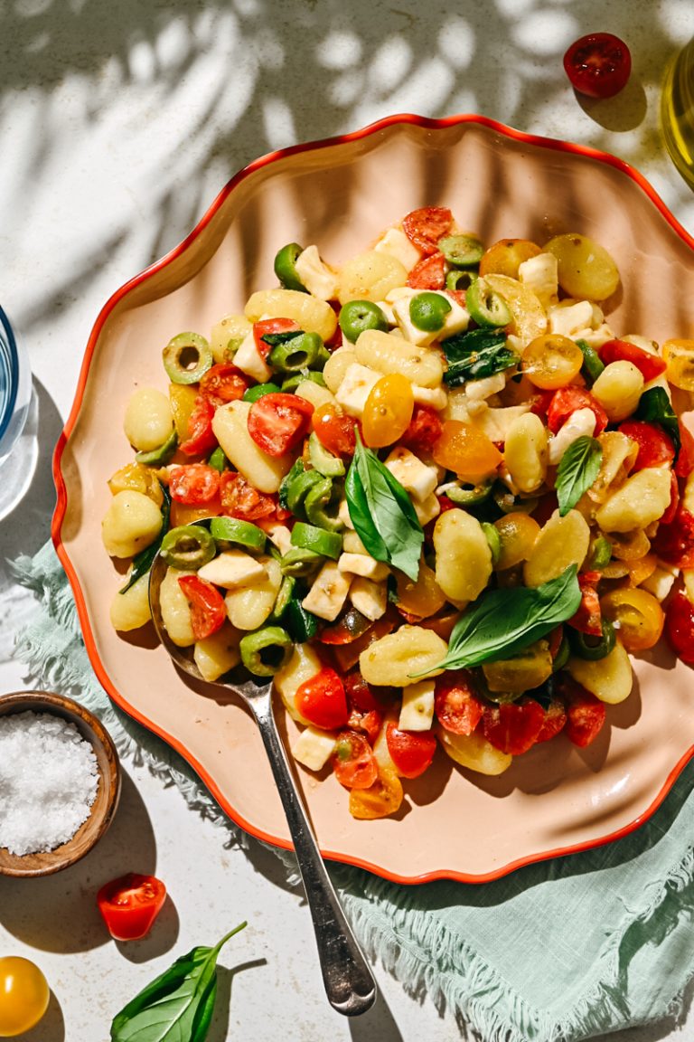 Fresh marinated tomato gnocchi salad served on an orange plate.