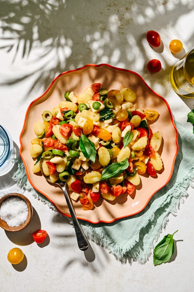 Overhead shot of marinated tomato gnocchi salad served on a plate with a spoon.