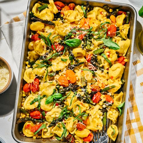 Overhead shot of summer sheet pan tortellini with tomatoes and corn.