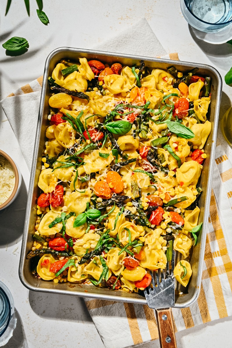Overhead shot of summer sheet pan tortellini with tomatoes and corn.
