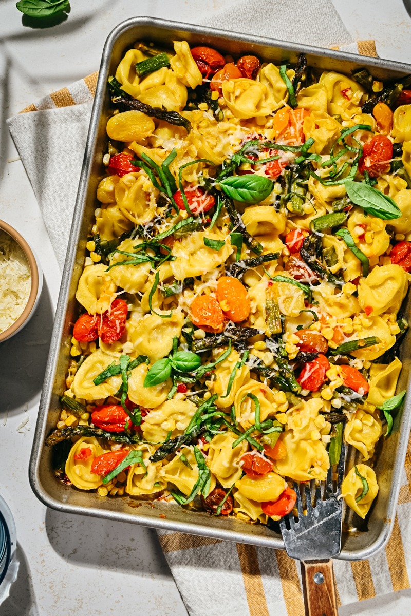 Summer sheet pan tortellini with parmesan and basil on top.
