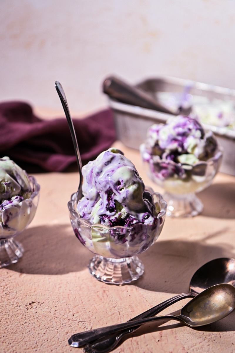Side view of three cups with scoops of blueberry basil ice cream in them.