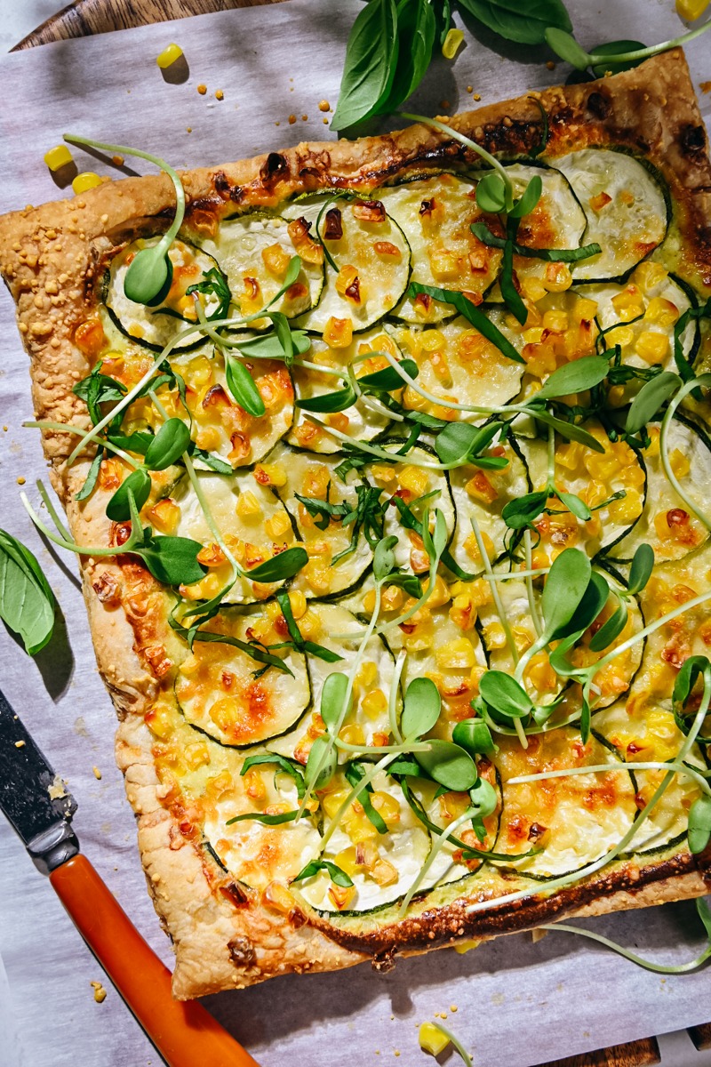 Zucchini tart on a piece of parchment paper garnished with microgreens.