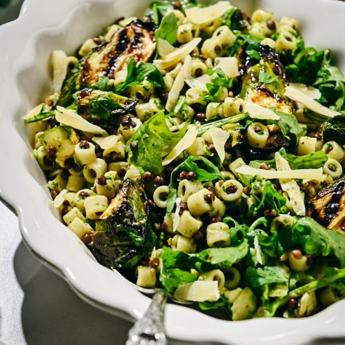Side view of a zucchini pasta salad served in a white bowl.