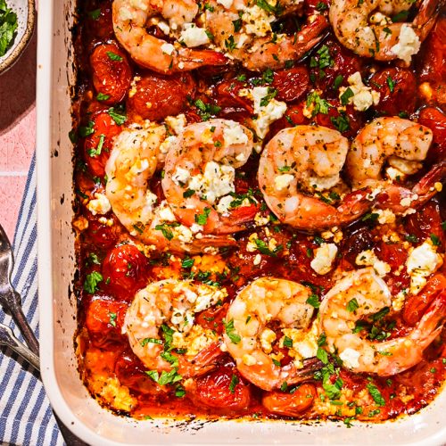 Shrimp saganaki in a baking dish, topped with feta and parsley.