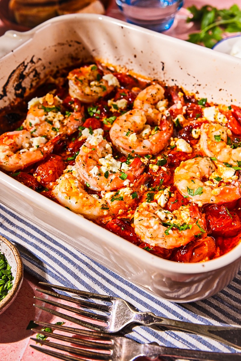 Side view of shrimp saganaki served in a baking dish on a linen.