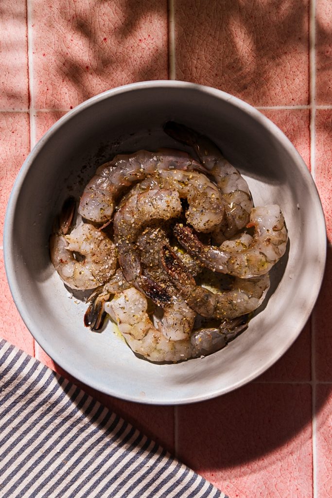 Large shrimp seasoned with spices in a bowl.