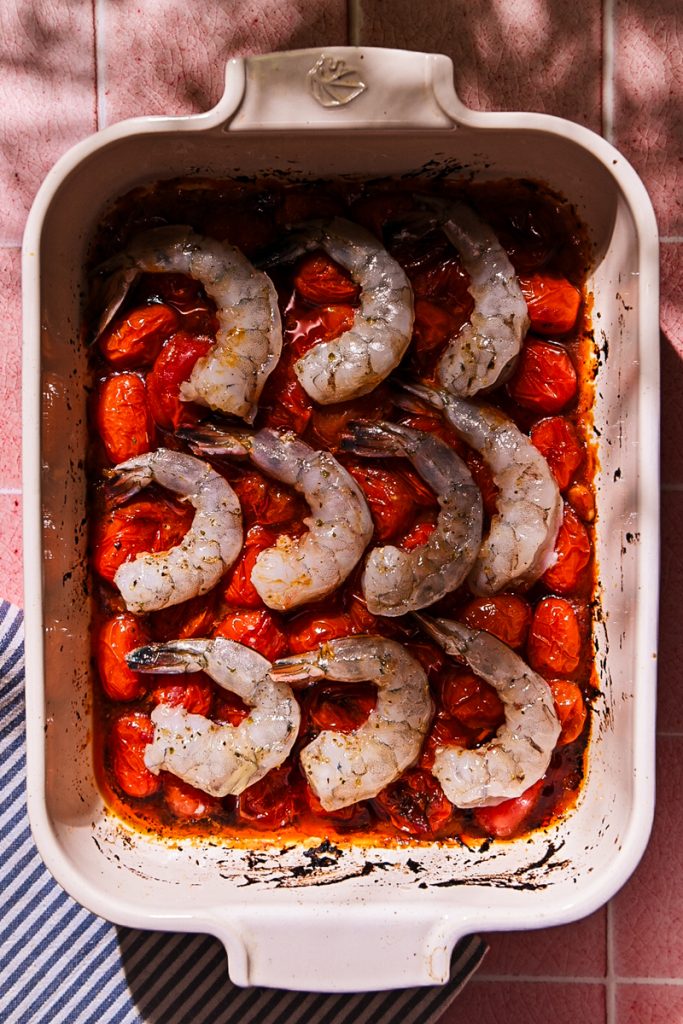 Shrimp nestled into the roasted tomatoes in a baking dish.
