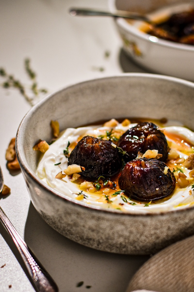 Side view of roasted figs over yogurt with walnuts and thyme.