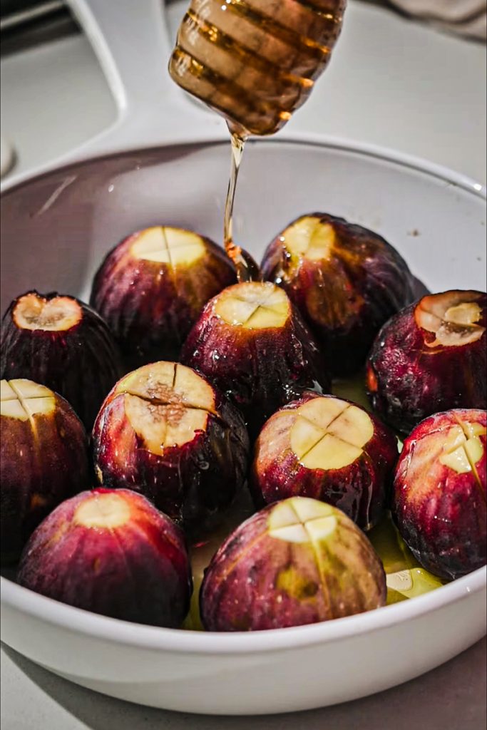 Fresh figs in a bowl with honey being drizzled over the top.