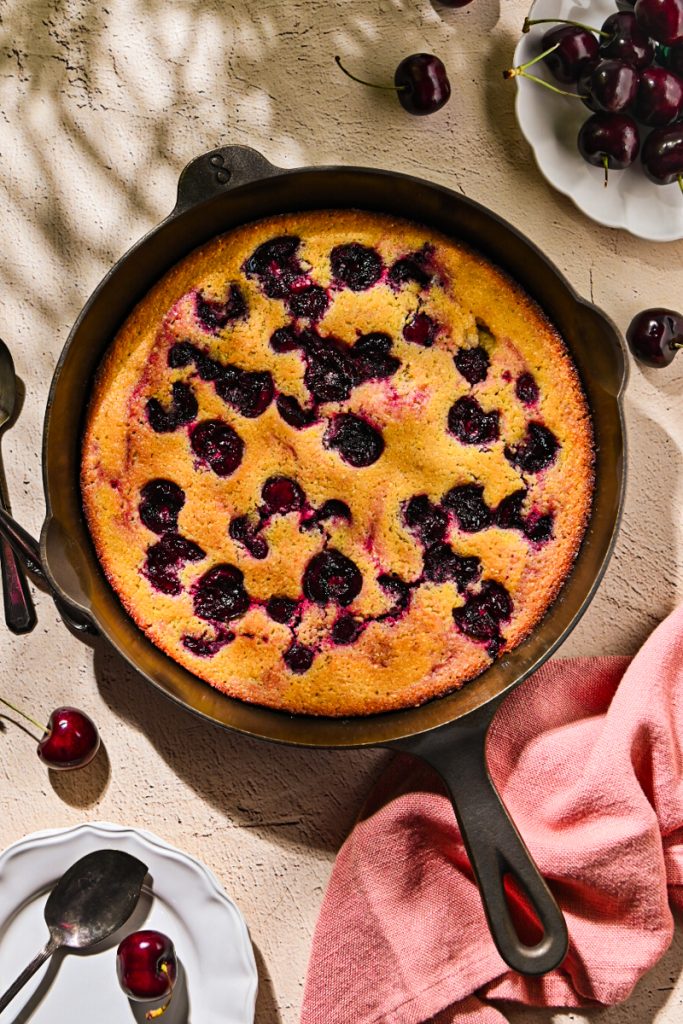 Overhead shot of a baked cherry spoon cake in a cast iron skillet.
