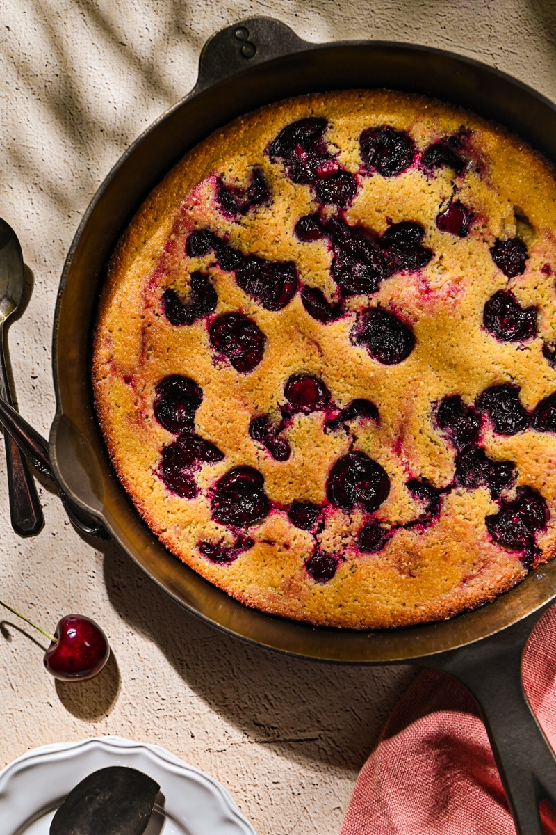 Close up of cherry spoon cake in a cast iron skillet.