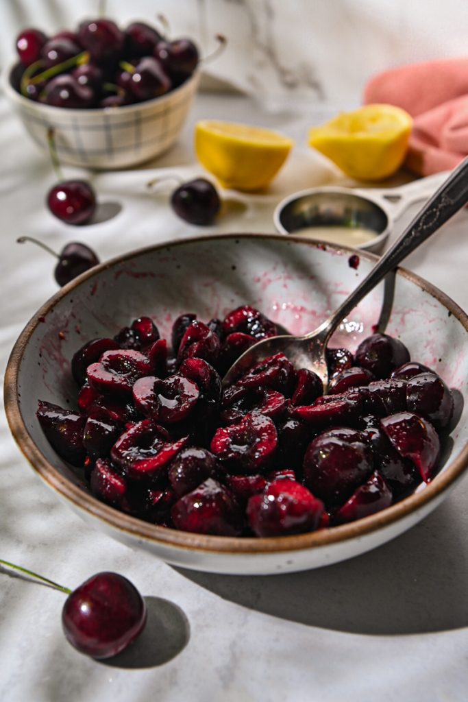 Mixing together cherries, sugar, lemon juice, and salt.
