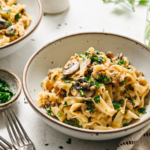 Side view of a bowl of ground veal stroganoff garnished with parsley.