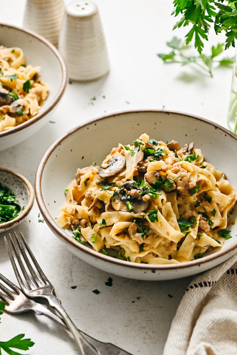 Side view of a bowl of ground veal stroganoff garnished with parsley.