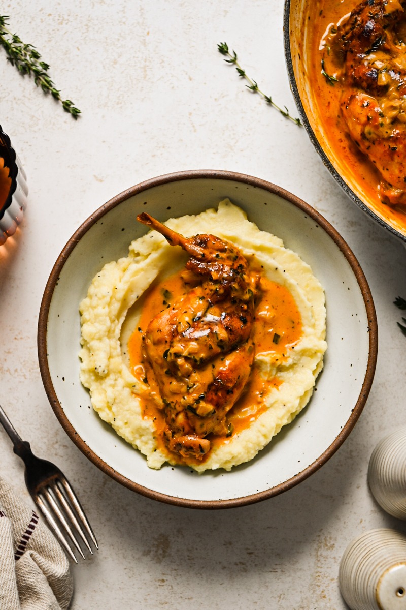 Lapin au vinaigre served on a bed of mashed potatoes in a bowl.