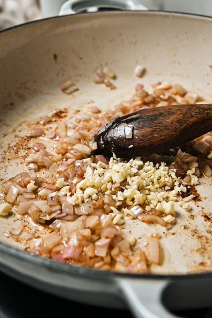 Garlic added to the shallots in a skillet.