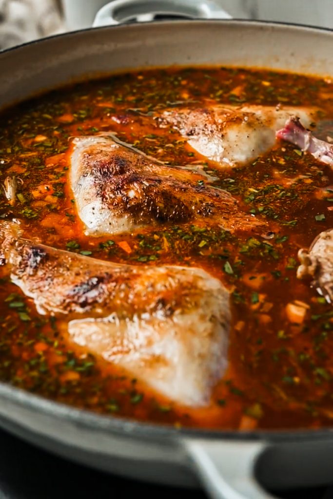 Rabbit added back to the liquid in a skillet to braise.