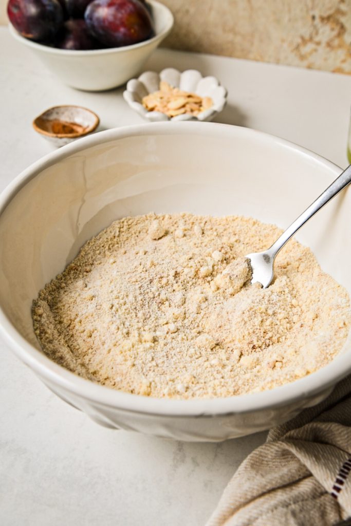 Dry ingredients including almond flour, flour, sugar, and cinnamon mixed together in a white bowl.
