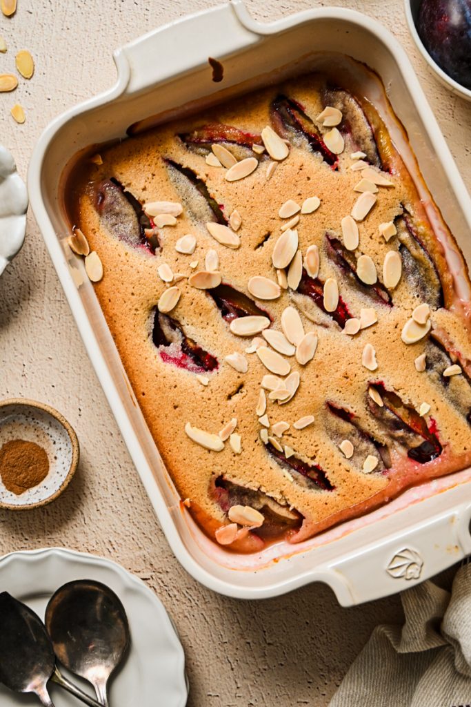 Baked Plum Almond Cake in a white dish topped with sliced almonds.